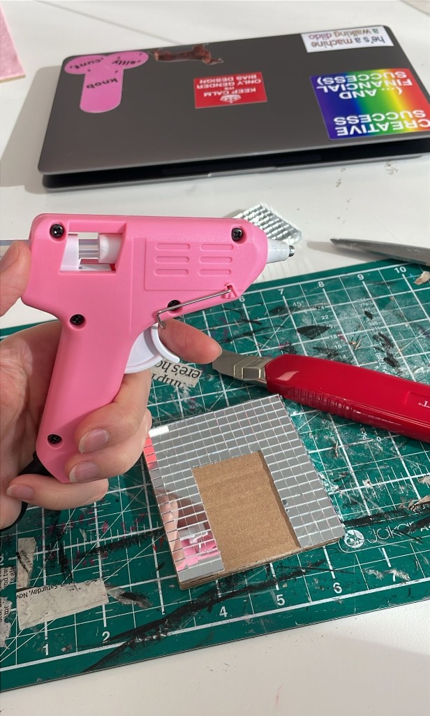 Work in progress — mirror tiles and glue gun on cutting mat
