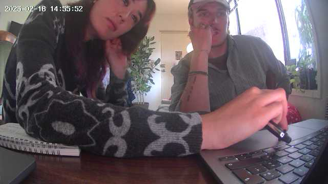 #Surveillancecore Pt.01 — wide-angle view of two people at a laptop, security-camera timestamp